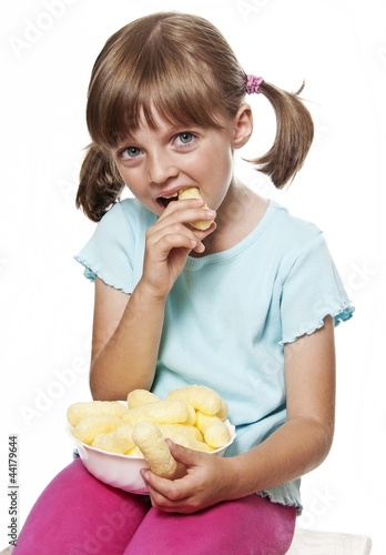 Photo: happy little girl eating corn nibbles snacks - white background happy little girl eating corn nibbles snacks - white background