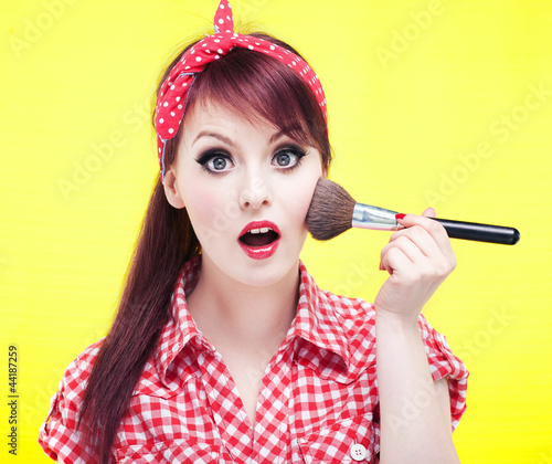Foto: Cute pin up girl applying blusher Cute pin up girl applying blusher