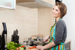 Woman in striped apron slices vegetables in the kitchen