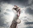 Male hand holding gold medal against the dramatic sky