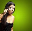 portrait of young woman surprised looking through a magnifying g