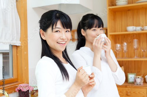 Photo: Beautiful young women relaxing in the kitchen. Portrait of asian Beautiful young women relaxing in the kitchen. Portrait of asian