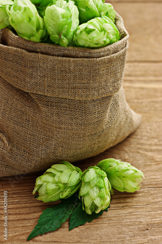 Photo: Hop in a burlap bag on wooden background Hop in a burlap bag on wooden background