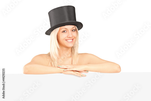 Photo: Young woman with a top hat posing behind a blank panel Young woman with a top hat posing behind a blank panel