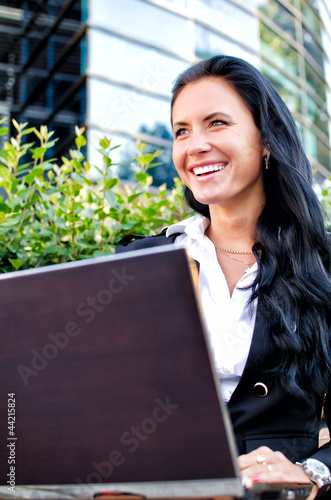 Photo: Attractive businesswoman with notebook in city park Attractive businesswoman with notebook in city park