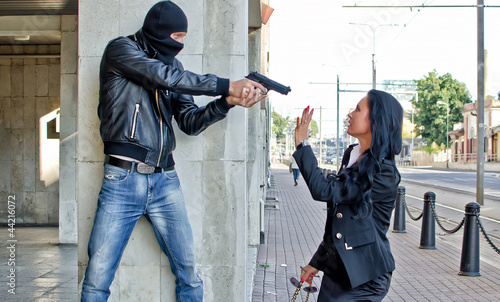 Photo: Bandit with a gun threatening young woman in the street Bandit with a gun threatening young woman in the street