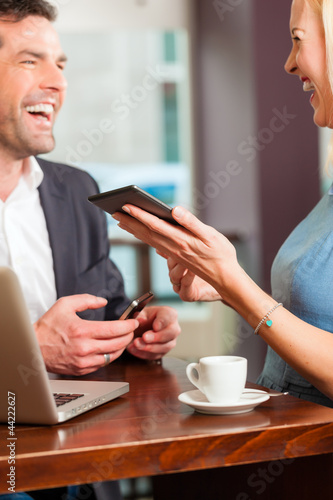 Photo: Working colleagues - man and woman - sitting in cafe Working colleagues - man and woman - sitting in cafe