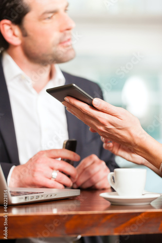 Photo: Working colleagues - man and woman - sitting in cafe Working colleagues - man and woman - sitting in cafe