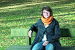 Foto: Woman sitting in autumnal park on the park bench Woman sitting in autumnal park on the park bench