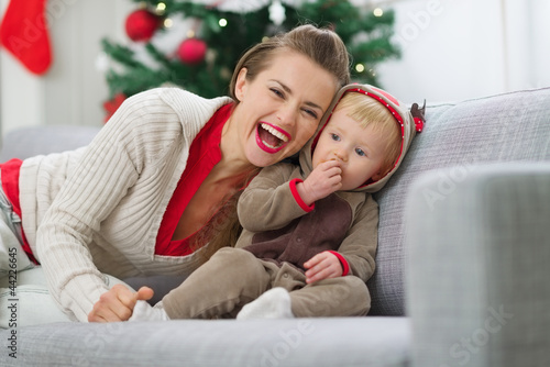 Photo: Smiling young mother and baby having fun time on Christmas Smiling young mother and baby having fun time on Christmas
