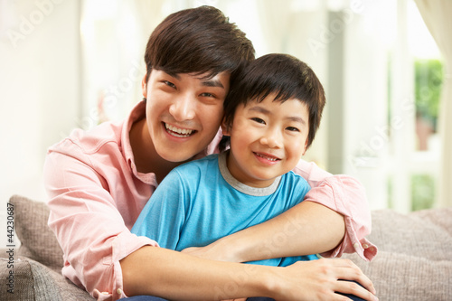 Photo: Chinese Father And Son Relaxing On Sofa At Home Chinese Father And Son Relaxing On Sofa At Home
