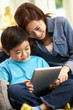 Chinese Mother And Son Using Tablet Computer Whilst Sitting On S