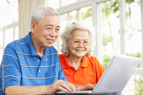 Photo: Senior Chinese Couple Sitting At Desk Using Laptop At Home Senior Chinese Couple Sitting At Desk Using Laptop At Home