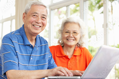 Photo: Senior Chinese Couple Sitting At Desk Using Laptop At Home Senior Chinese Couple Sitting At Desk Using Laptop At Home