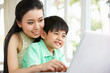 Chinese Mother And Son Sitting At Desk Using Laptop At Home