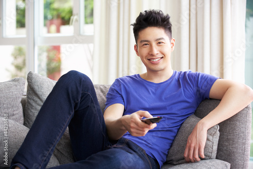 Photo: Young Chinese Man Sitting And Watching TV On Sofa At Home Young Chinese Man Sitting And Watching TV On Sofa At Home
