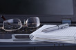 Black notebook with notepad pen and glasses lying on it