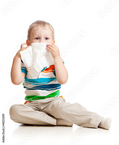Photo: kid cleaning nose with tissue isolated on white kid cleaning nose with tissue isolated on white