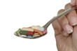 Hand hält Löffel mit verschiedenen bunten Tabletten