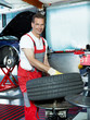 Car mechanic in a garage is fitting a summer tyre