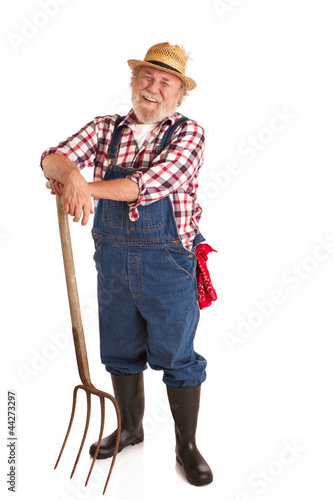 Photo: Cheerful senior farmer leaning on hay fork Cheerful senior farmer leaning on hay fork