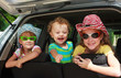 two little girls  and boy sitting in the car with backpacks