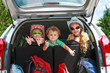 two little girls  and boy sitting in the car with backpacks