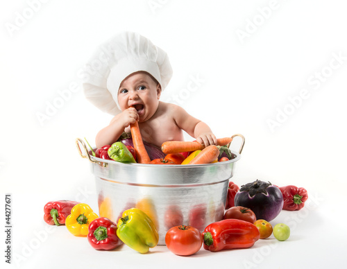 Photo: Bambino con cappello da cuoco dentro la pentola con ortaggi Bambino con cappello da cuoco dentro la pentola con ortaggi