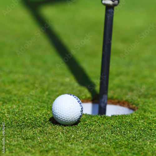 Photo: golf ball on lip of cup golf ball on lip of cup