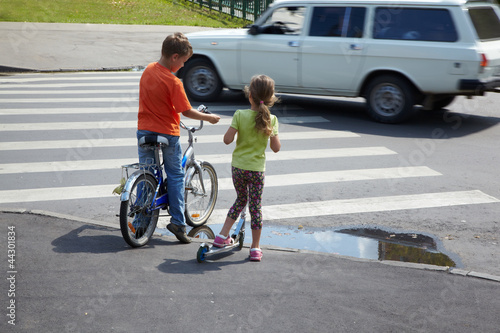 Photo: Boy with bicycle and his younger sister with scooter stand Boy with bicycle and his younger sister with scooter stand
