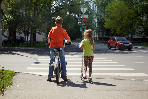 Photo: Boy with bicycle and his younger sister with scooter Boy with bicycle and his younger sister with scooter