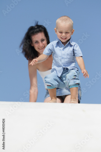 Photo: outdoor portrait of young happy mother playing with child isolat outdoor portrait of young happy mother playing with child isolat