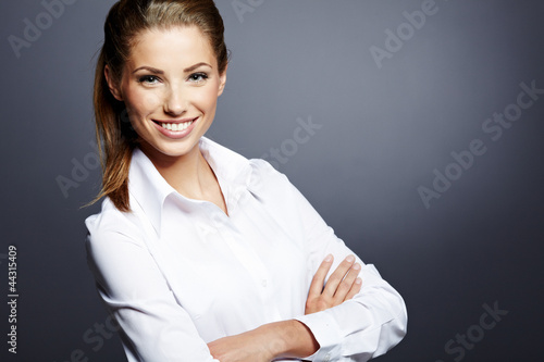 Photo : Portrait of a beautiful young business woman standing against gr Portrait of a beautiful young business woman standing against gr