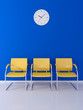 A wall clock and 3 stools in the blue waiting room
