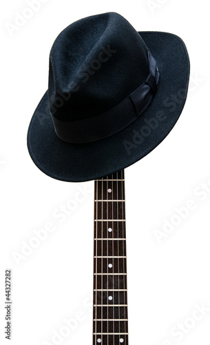 Photo: Vintage hat resting on a guitar fretboard isolated background Vintage hat resting on a guitar fretboard isolated background