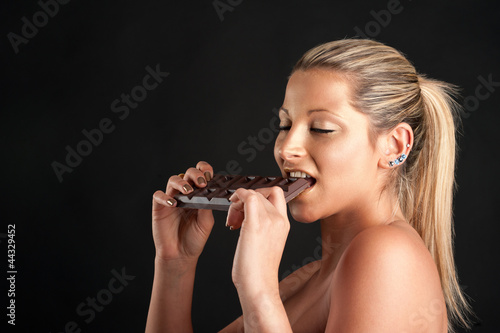 Photo: Beautiful woman with golden make up eating chocolate Beautiful woman with golden make up eating chocolate