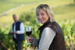Woman standing in vine rows with glass of wine