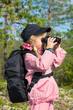 Little girl in a forest looking through binoculars