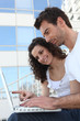 Couple with glass building in front of computer