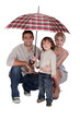 Young family sheltering under an umbrella