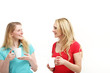 Two young women standing chatting over a cup of coffee
