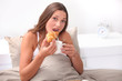 Woman eating a croissant in bed