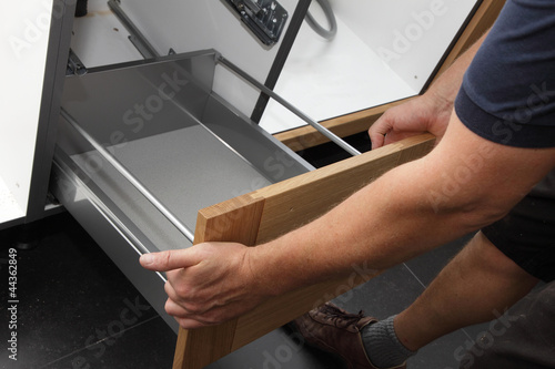 Photo: homme installant cuisine équipée homme installant cuisine équipée