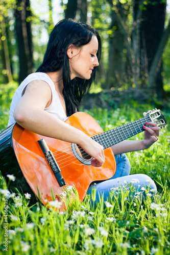Photo: Young woman playing the guitar outdoors Young woman playing the guitar outdoors