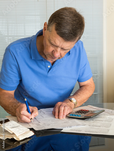 Photo: Senior man preparing USA tax form 1040 for 2012 Senior man preparing USA tax form 1040 for 2012