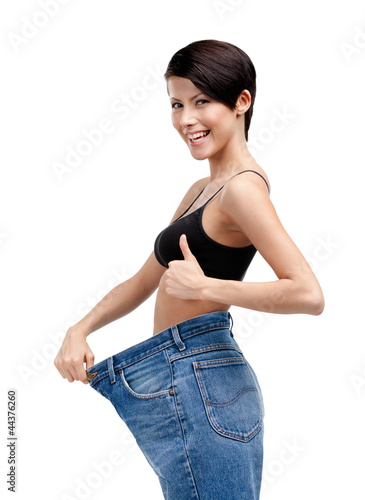 Photo: Slender woman wearing enormous jeans, isolated on white Slender woman wearing enormous jeans, isolated on white