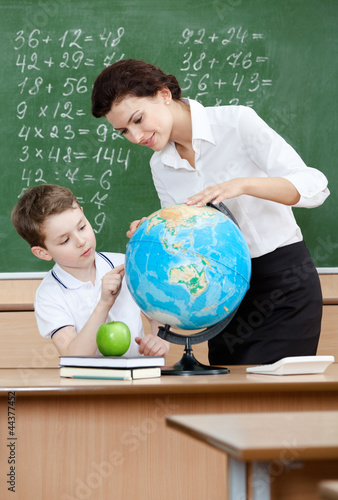 Photo: Geography teacher shows something to the pupil at the globe Geography teacher shows something to the pupil at the globe
