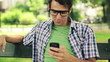 Video: Happy young man using smartphone in park, steadicam shot Happy young man using smartphone in park, steadicam shot