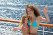 Mother and little daughter dressed in swimsuits wave their hands