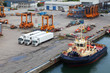 Foto: White lorries and orange loaders stand in port. White lorries and orange loaders stand in port.
